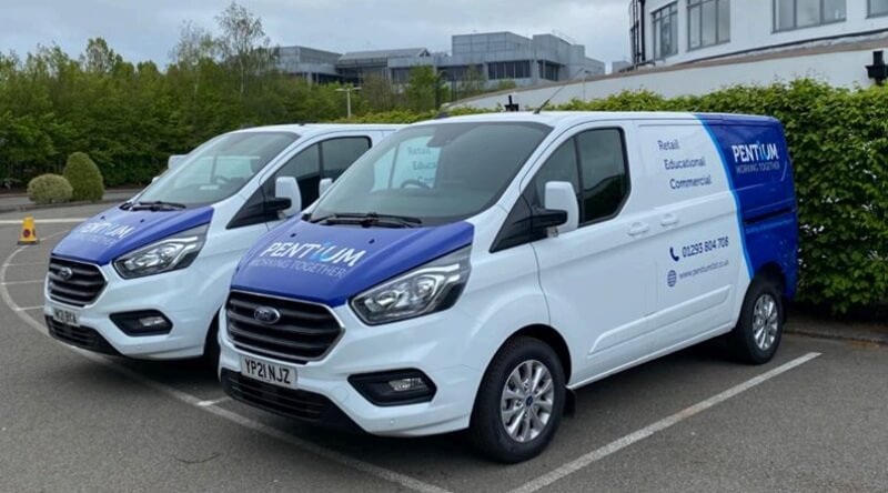 An image of the blue Pentium vehicle graphics on white vans.